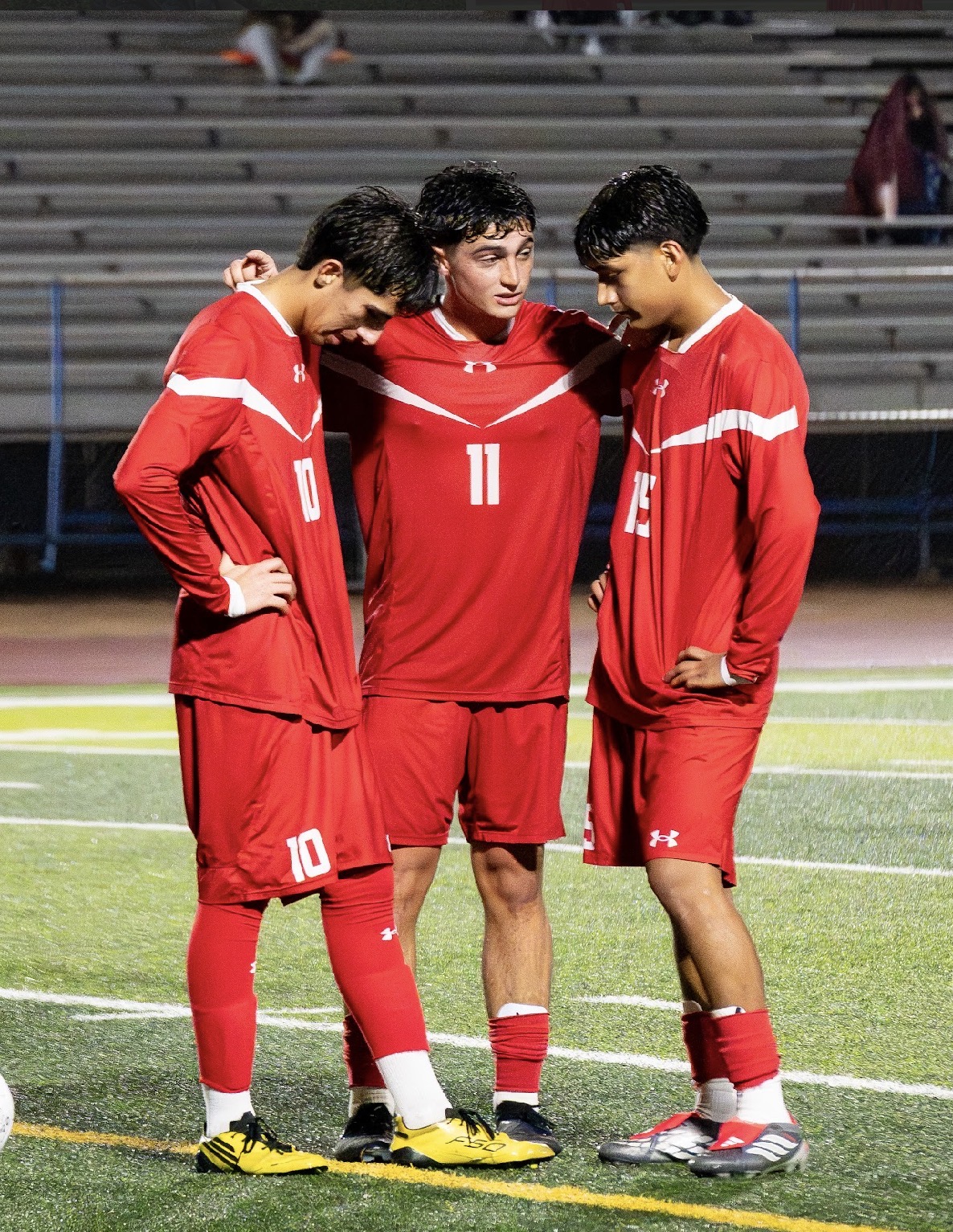 Three Mountain View boys soccer teammates together under the lights
