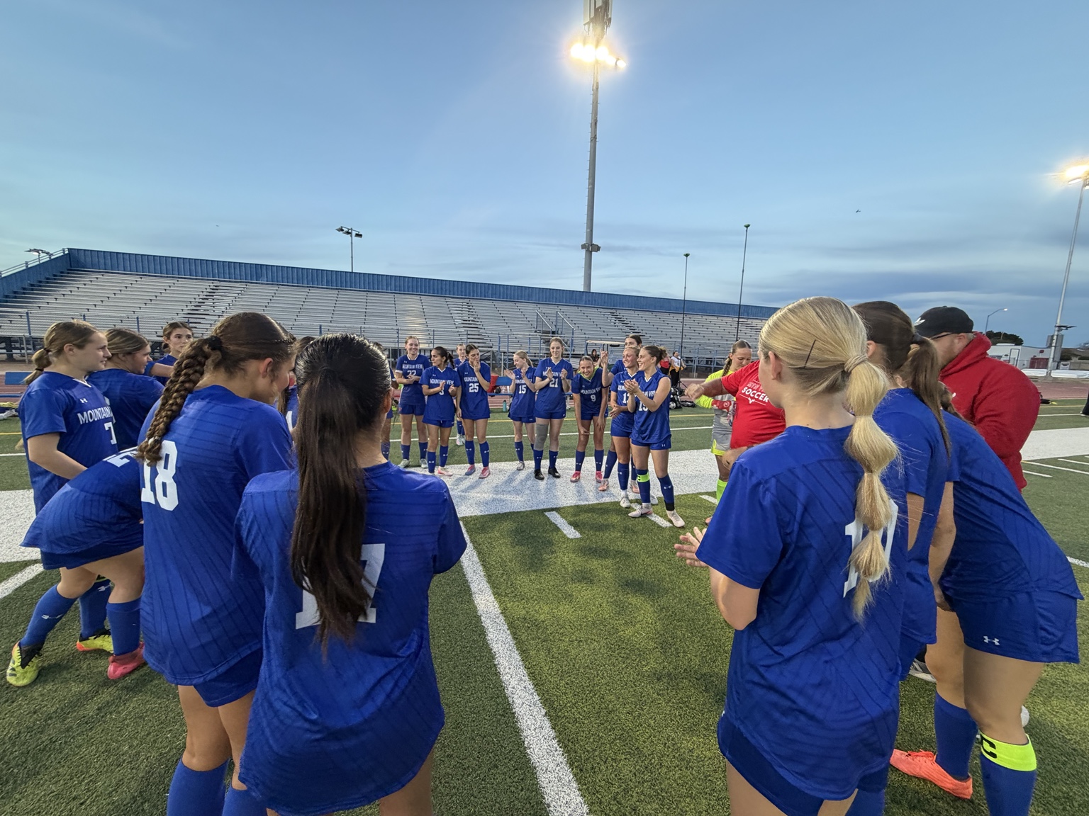 Mountain View girls soccer team gathered in a circle on the field